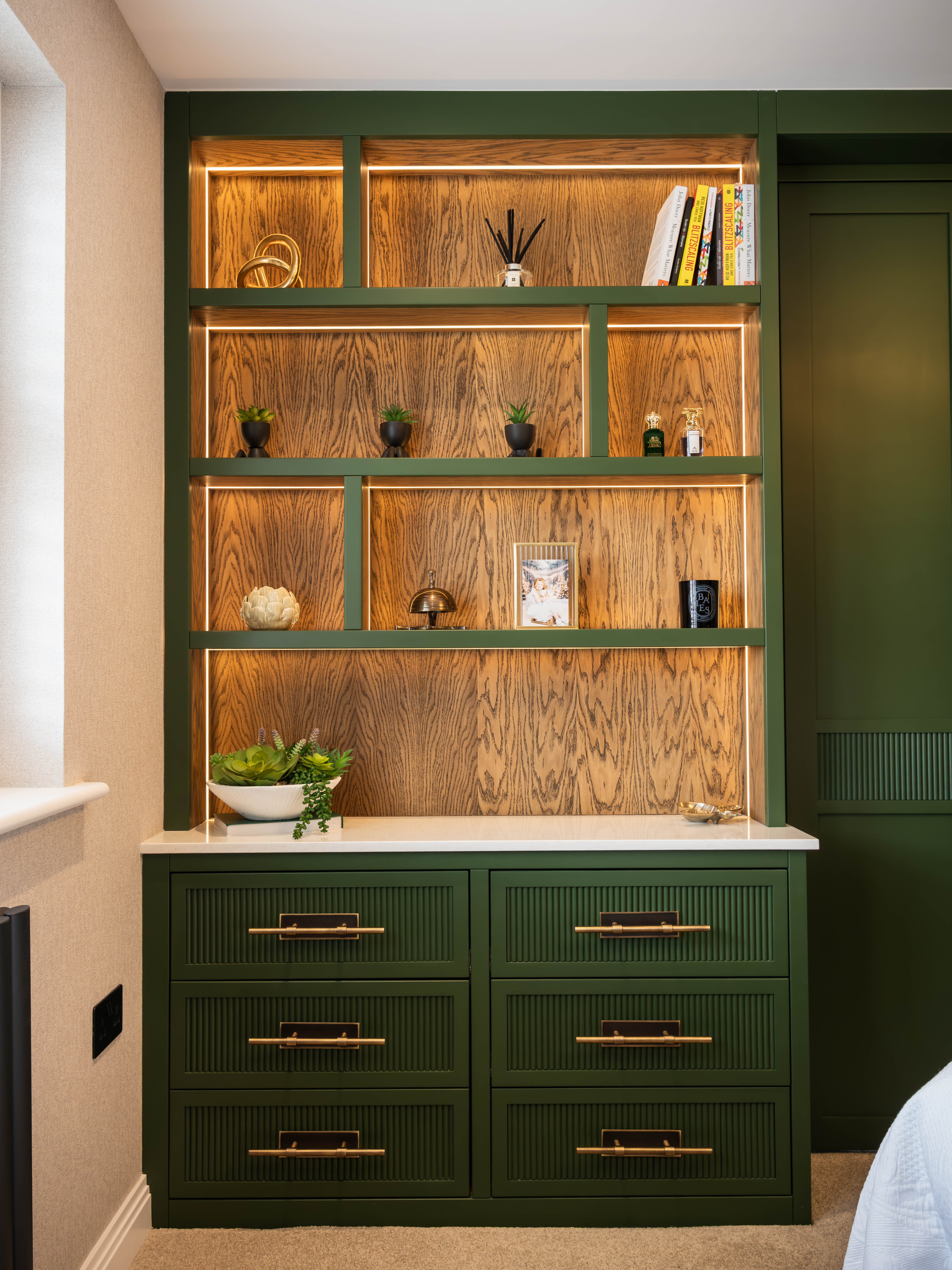 Bespoke LED-lit shelving with warm oak backing — Farrow and Ball green fitted bedroom Manchester by Hafferty Interiors