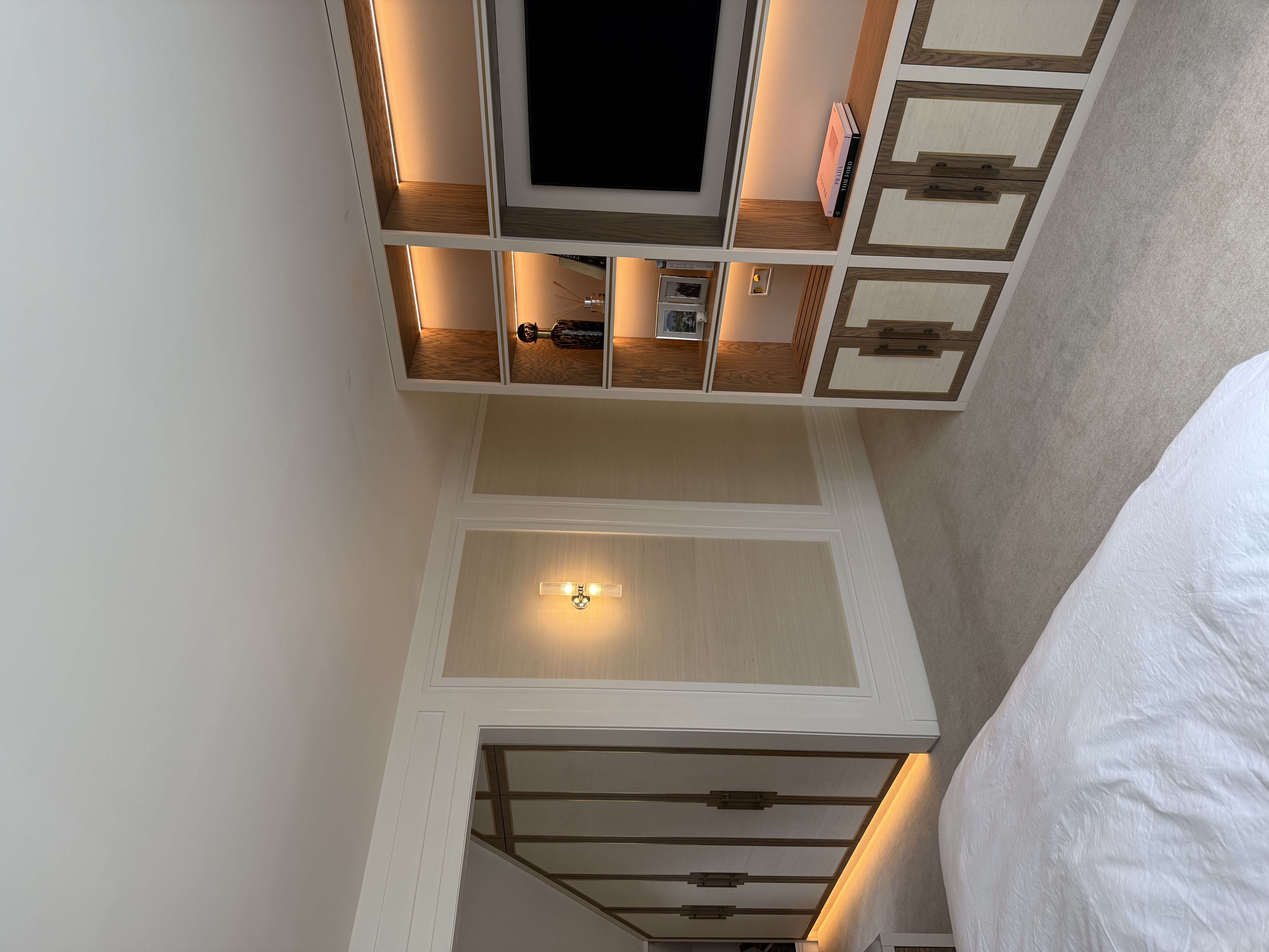Bespoke fitted bedroom media wall with warm LED shelving glow — Hafferty Interiors Manchester