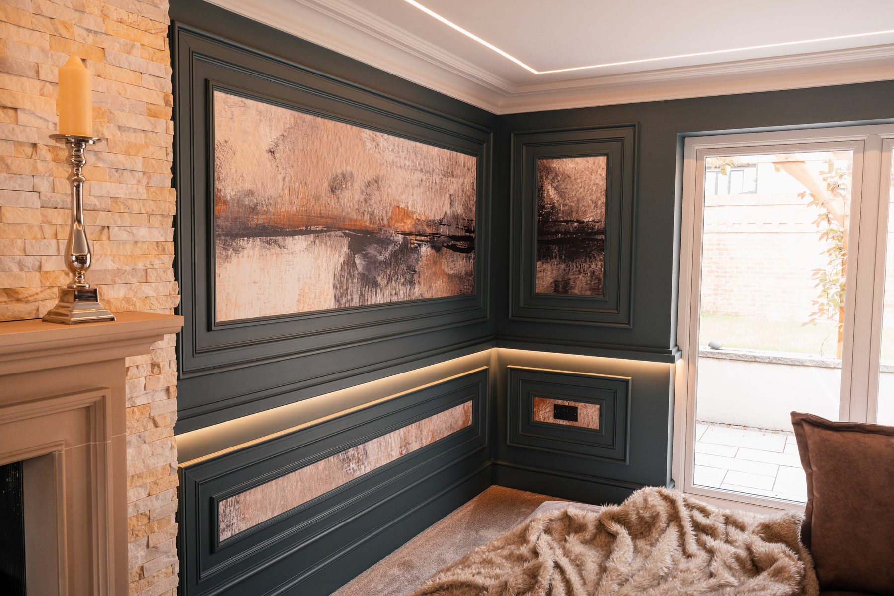 Natural stacked stone fireplace surround alongside dark panelled walls and LED lighting — Boothstown by Hafferty Interiors