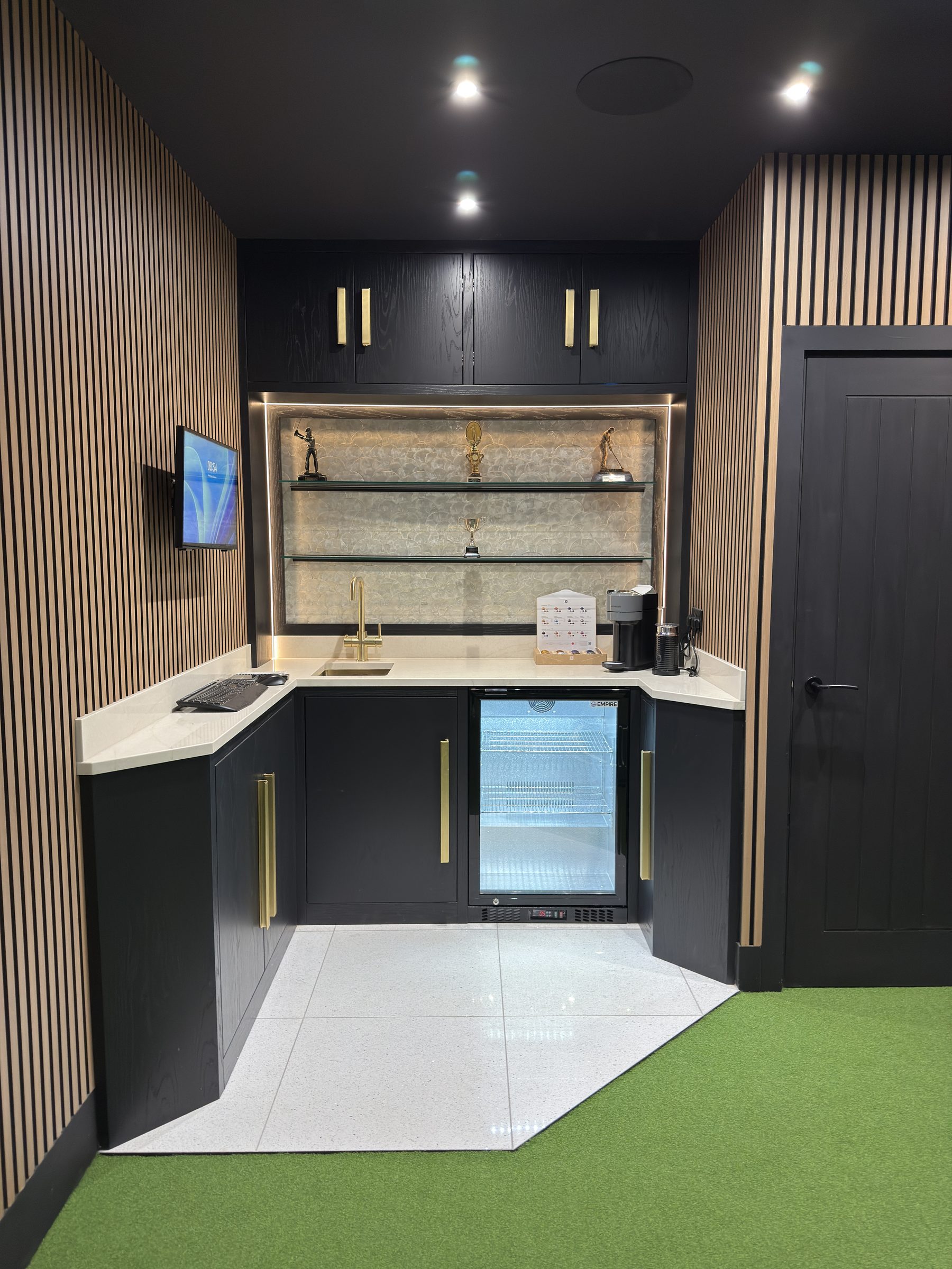 Black oak bar cabinetry with integrated fridge — bespoke golf simulator home bar by Hafferty Interiors