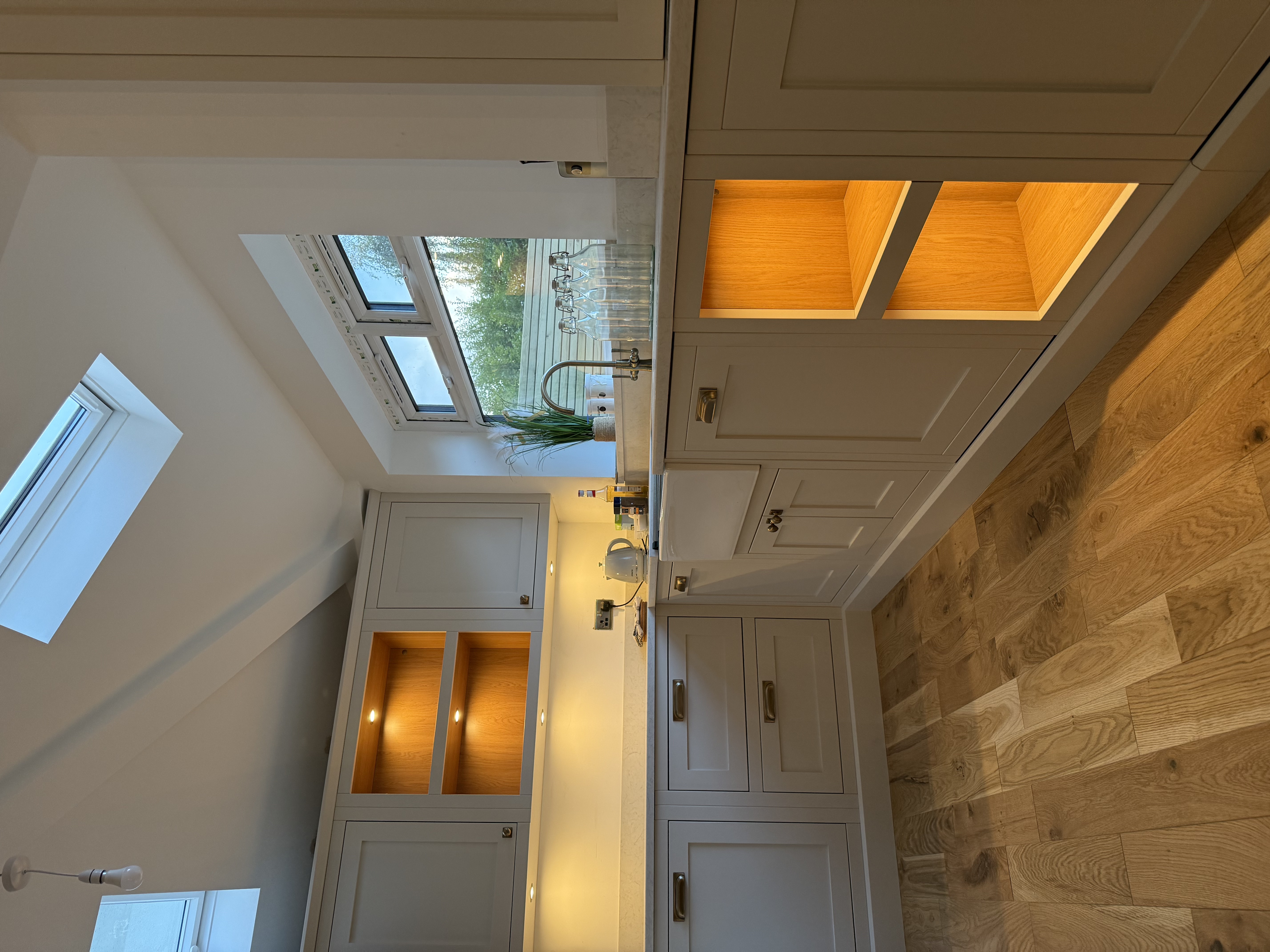 Bespoke in-frame kitchen in Cheadle with Velux skylights, warm LED-lit oak niches and Belfast sink — Hafferty Interiors