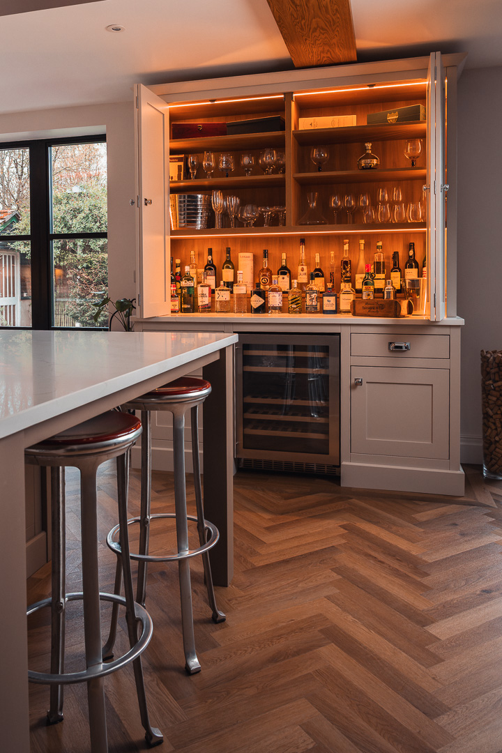 Bespoke fold-open drinks and larder cabinet with warm oak interior, LED lighting and integrated wine fridge — in-frame kitchen by Hafferty Interiors