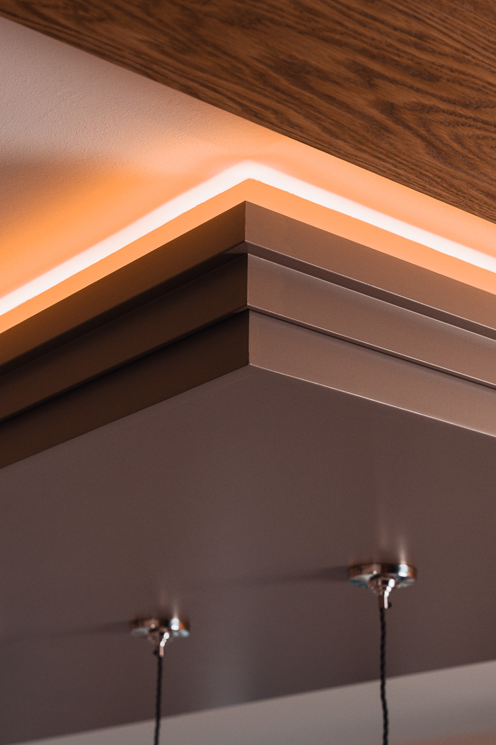 Bespoke painted island coffer cornice with warm LED halo detail — in-frame kitchen by Hafferty Interiors