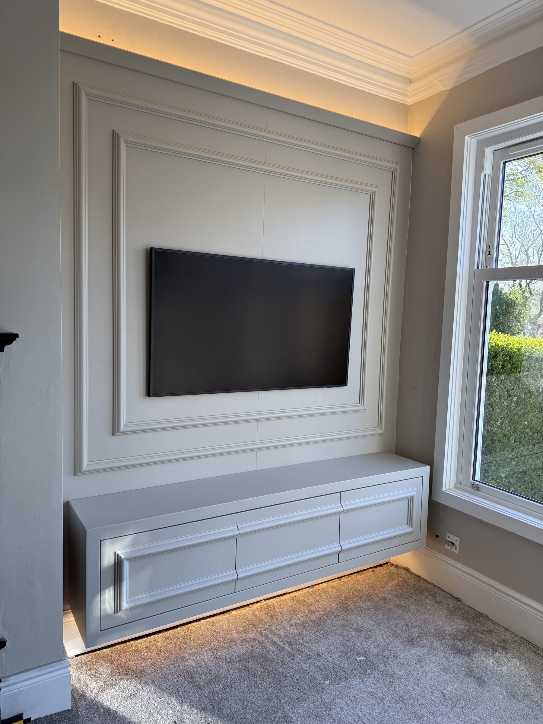 Bespoke fitted painted media wall with panelled TV surround and floating moulded drawer unit — Hafferty Interiors
