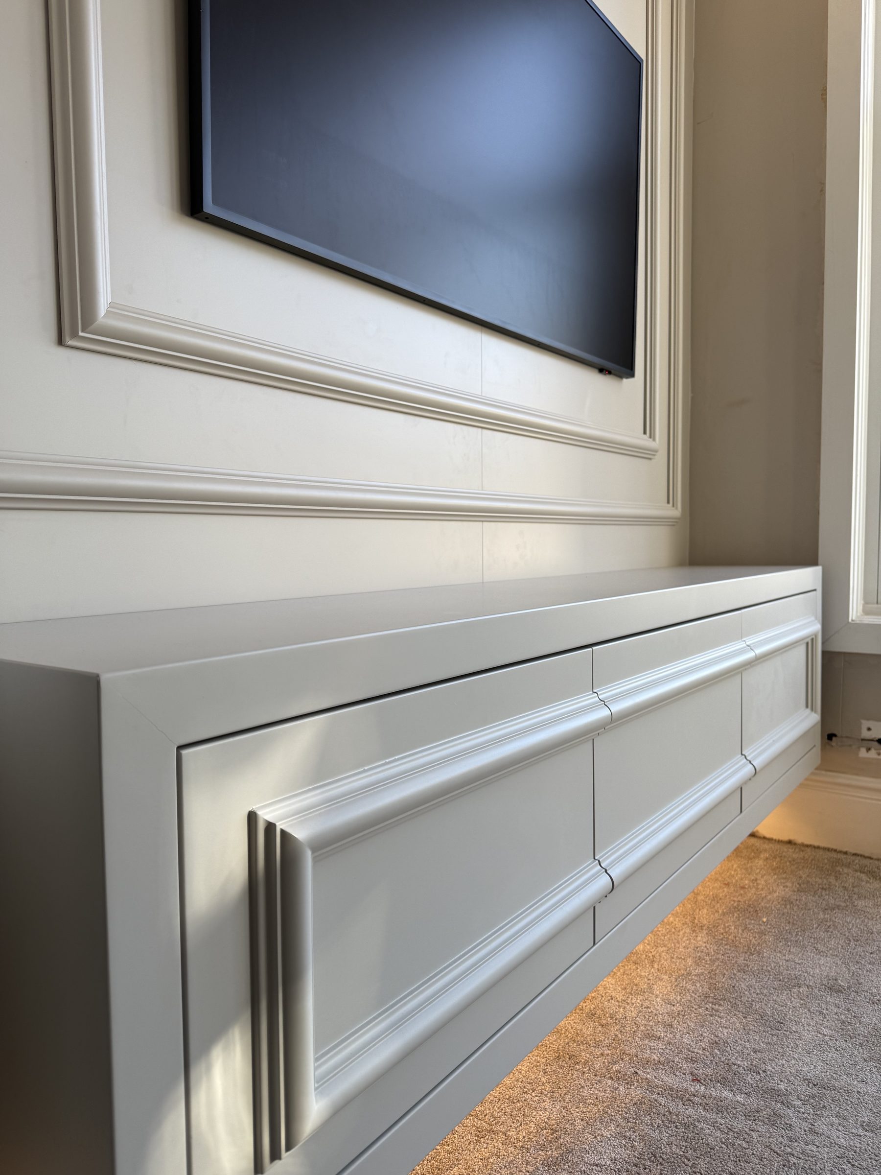 Close-up of moulded push-to-open drawer fronts on bespoke floating media unit — Hafferty Interiors