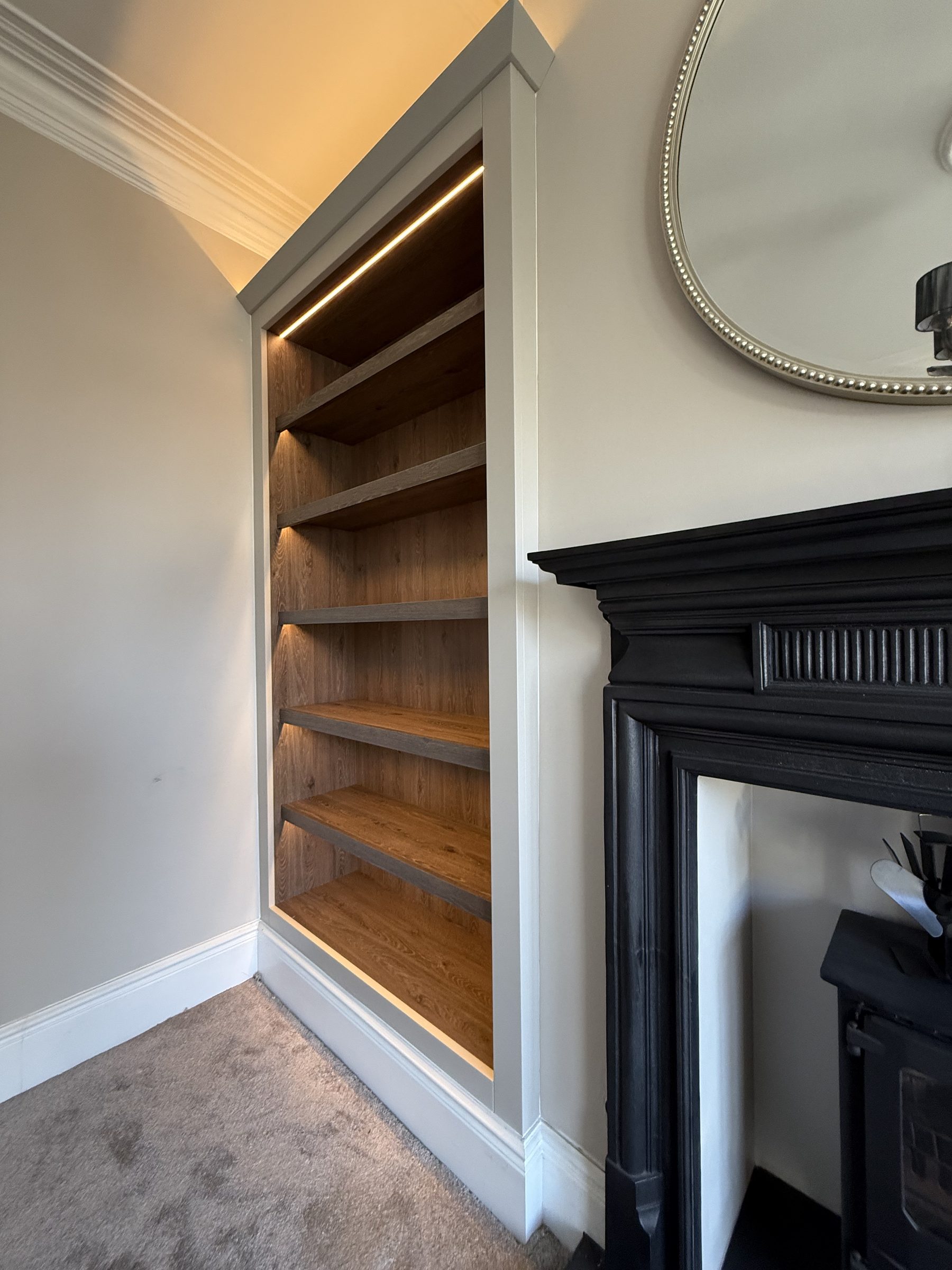 Bespoke lit oak alcove bookcase with LED cove lighting and painted surround — Hafferty Interiors
