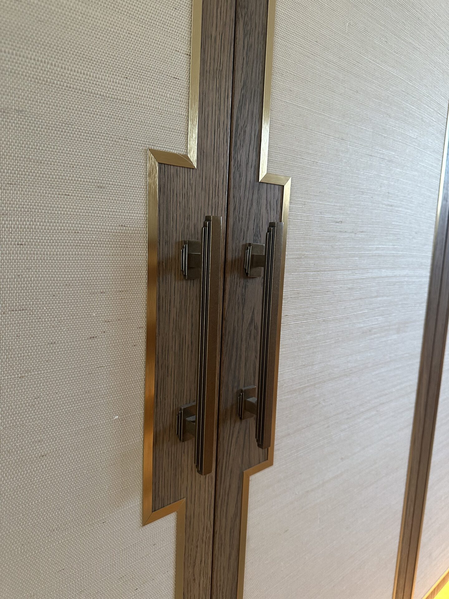 Bespoke wardrobe door with brass inlay and textured wallpaper panel — Hafferty Interiors master suite