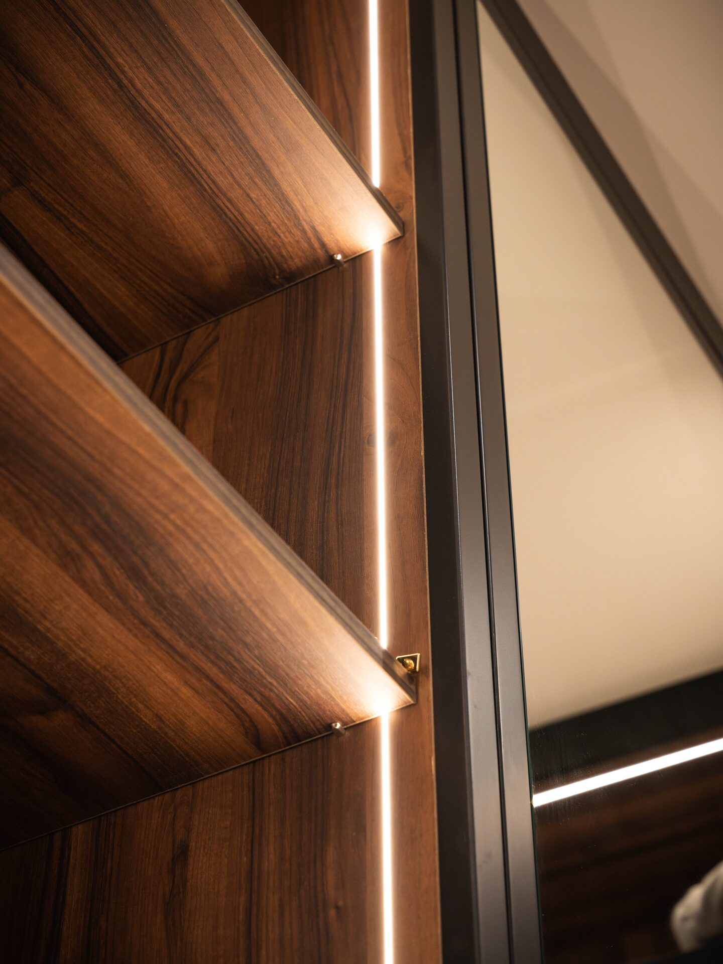 Seamless LED lighting throughout walnut walk-in wardrobe — Hafferty Interiors Manchester