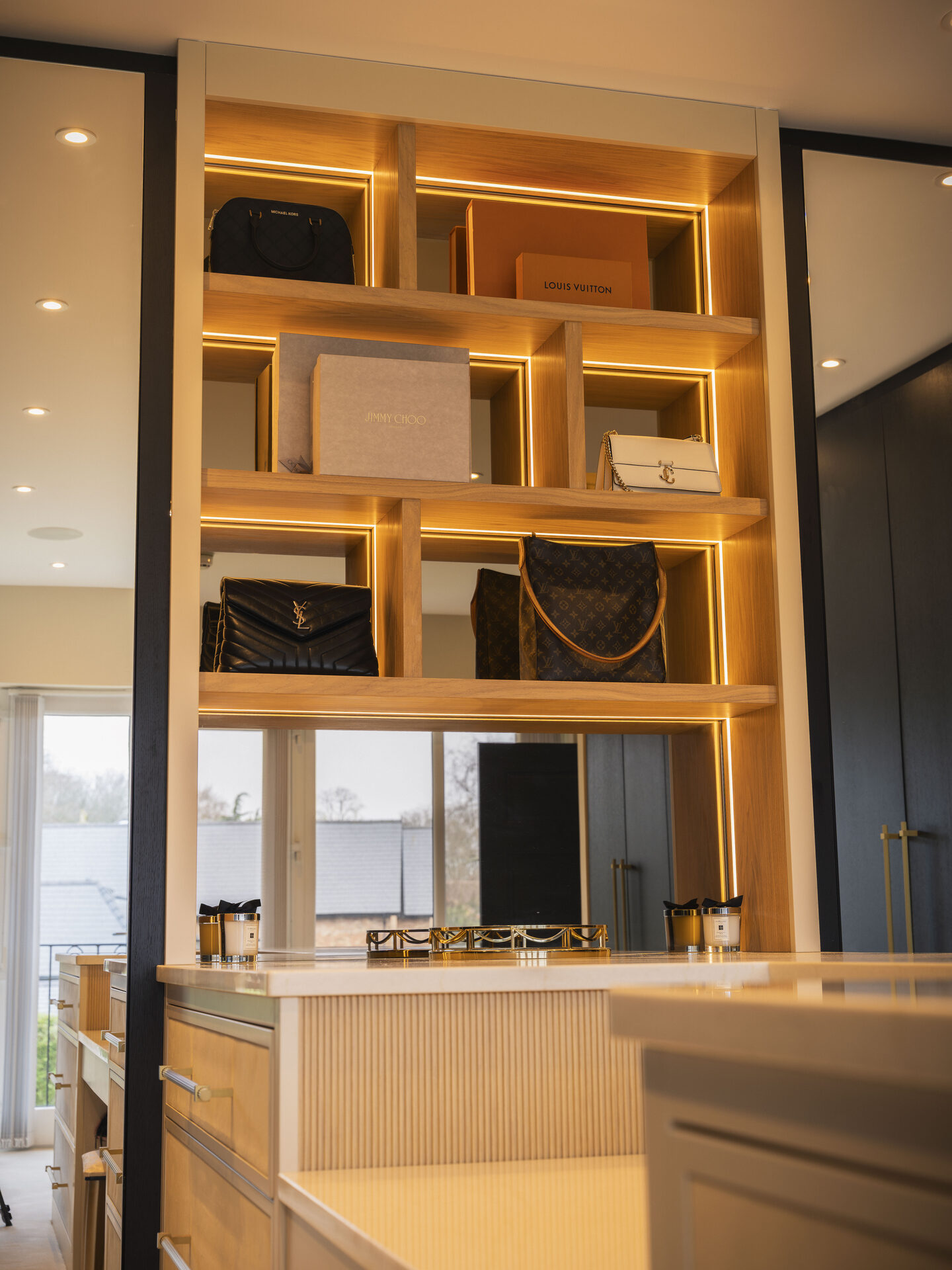 Bespoke display shelving with integrated lighting — walk-in wardrobe by Hafferty Interiors